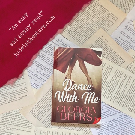 On a backdrop of book pages, a paperback of Dance With Me by Georgia Beers. In the top left corner of the image, a strip of torn paper with a quote: "An easy and sunny read." and a URL: judeinthestars.com.