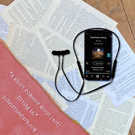 On a backdrop of book pages, an iPhone with the cover of Manhattan Moon by Jae, narrated by Abby Craden. In the bottom left corner of the image, a strip of torn paper with a quote: "A short romance about (not) fitting in." and a URL: judeinthestars.com.