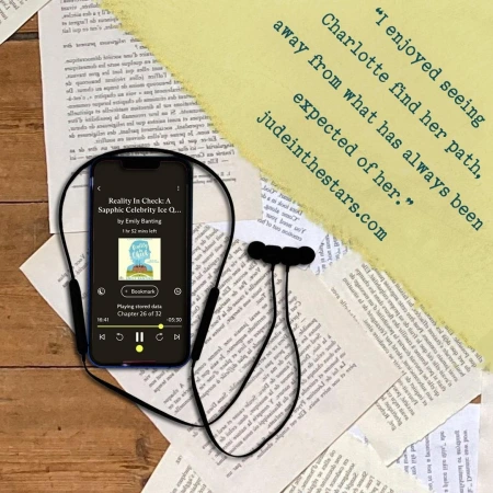 On a backdrop of book pages, an iPhone with the cover of Reality in Check (A South Downs Romance #2) by Emily Banting, narrated by Angela Dawe. In the top right corner of the image, a strip of torn paper with a quote: "I enjoyed seeing Charlotte find her path, away from what has always been expected of her." and a URL: judeinthestars.com.